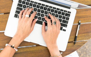 A woman engaged in typing on her laptop at a table, showcasing concentration in a comfortable workspace.