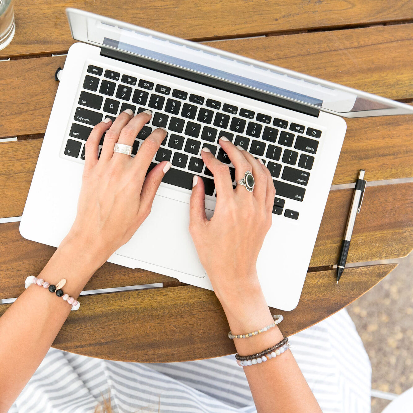 A woman engaged in typing on her laptop at a table, showcasing concentration in a comfortable workspace.