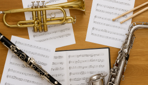 A saxophone, clarinet, and music sheet arranged on a table, highlighting instruments for a band fundraiser event.